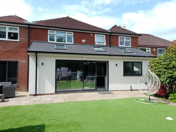 Modern two-storey house with a garden and patio area on a sunny day.
